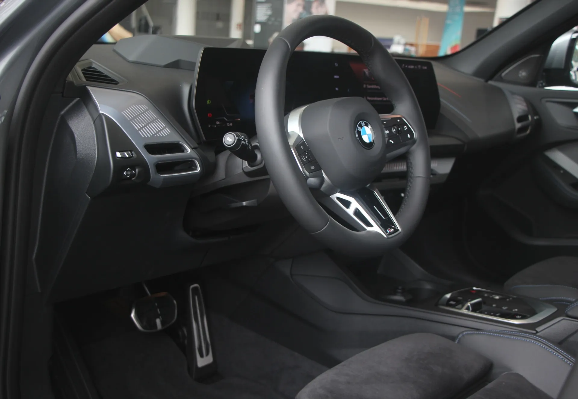 BMW 1シリーズ（F70型）の運転席まわり。湾曲した一体型ディスプレイとMスポーツ・ステアリング・ホイール