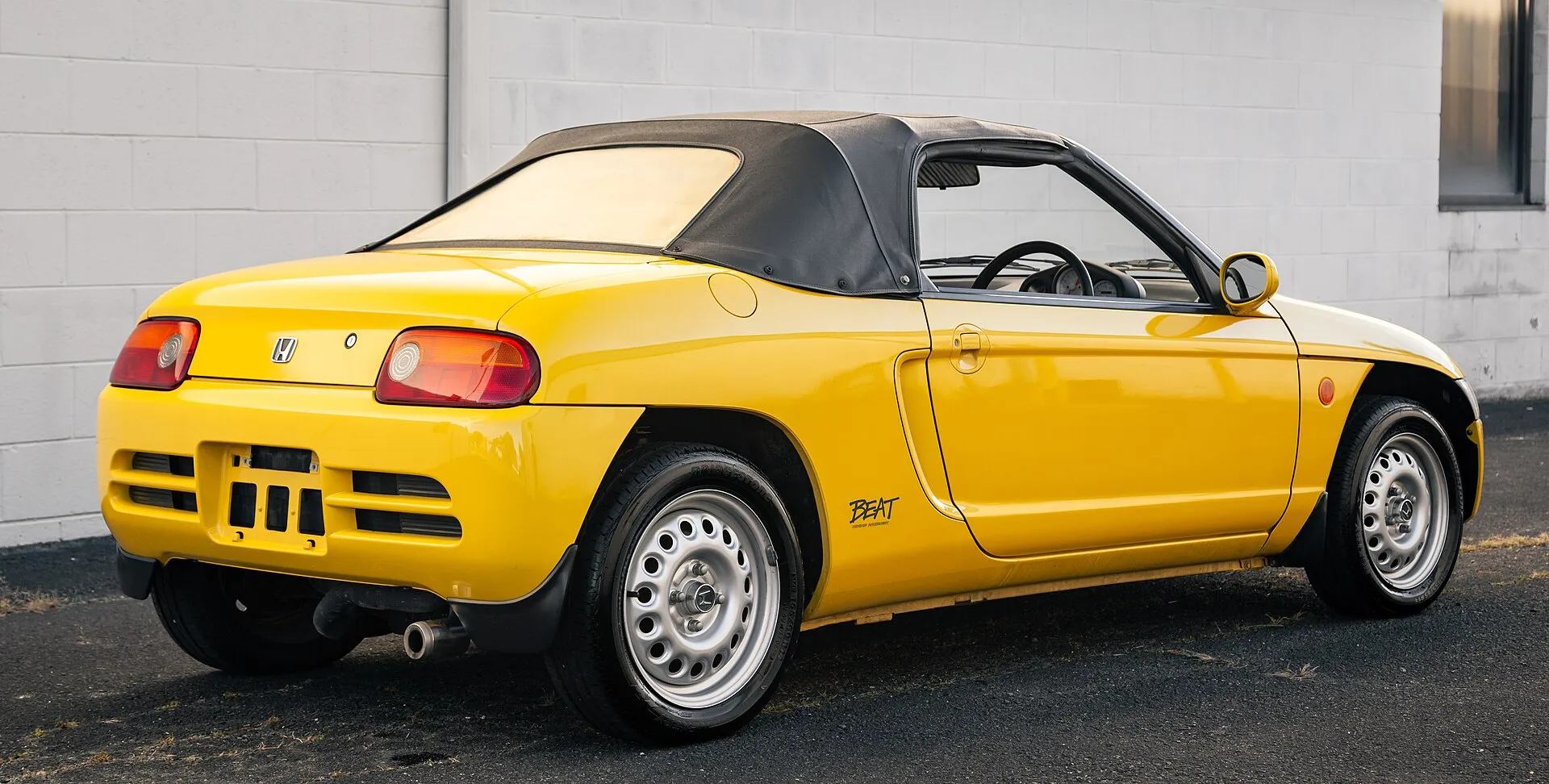 黄色いホンダ ビート（E-PP1）を斜め後ろから見た外観。左右のテールランプのあいだにホンダのHマークがあり、バンパーには横向きのスリットが並ぶ