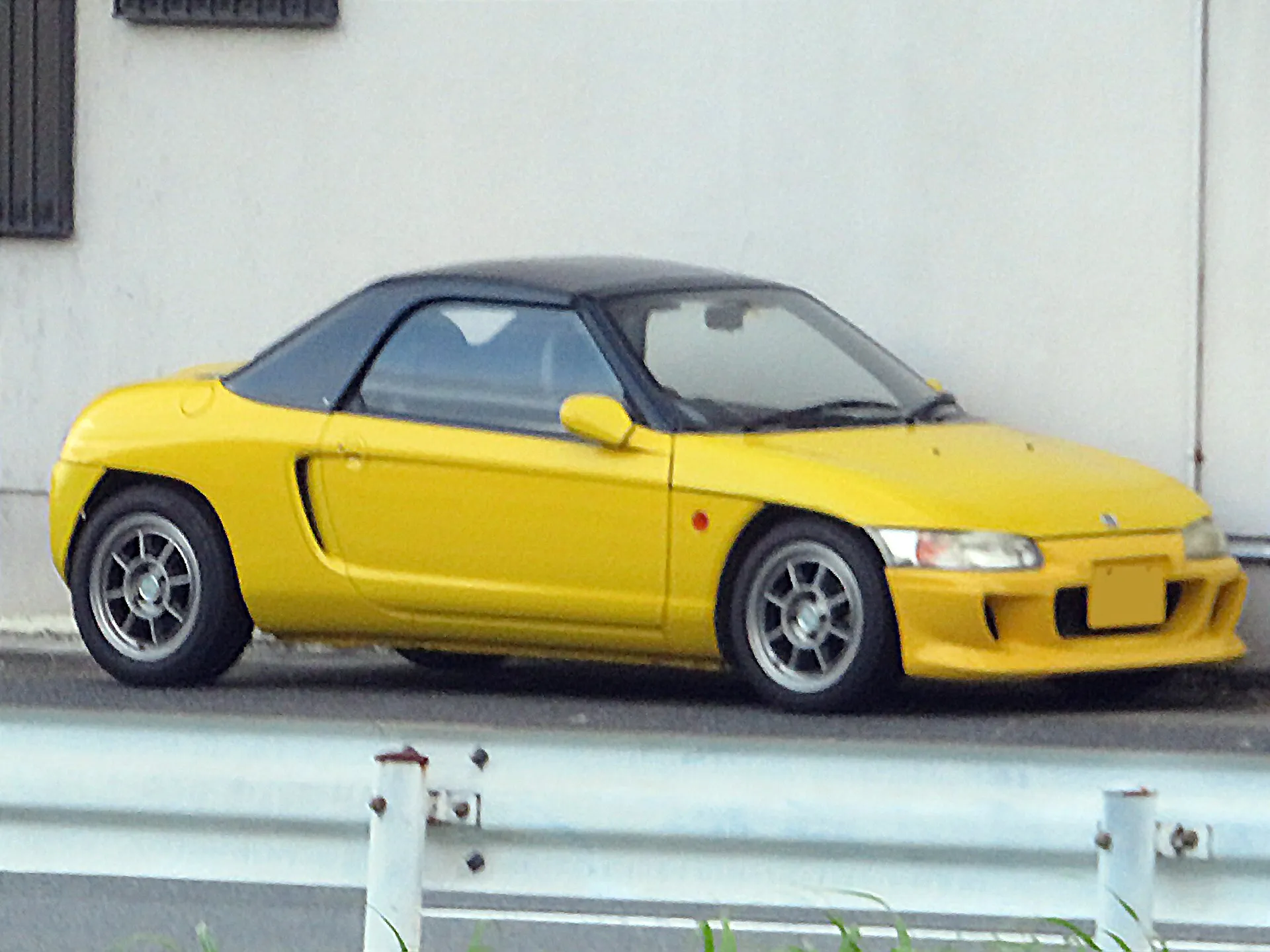 黄色いホンダ ビート（E-PP1）を右側面から見た外観。ソフトトップを閉じた状態で、道路脇に停車している