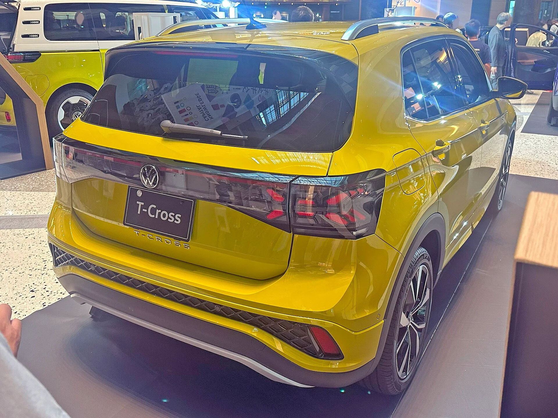 3BA-C1DKR型のフォルクスワーゲン T-Cross TSI R-Line を右後ろから見た外観。イエローのボディに横一文字のLEDテールランプが入り、テールゲート下端にT-CROSSのロゴが並ぶ