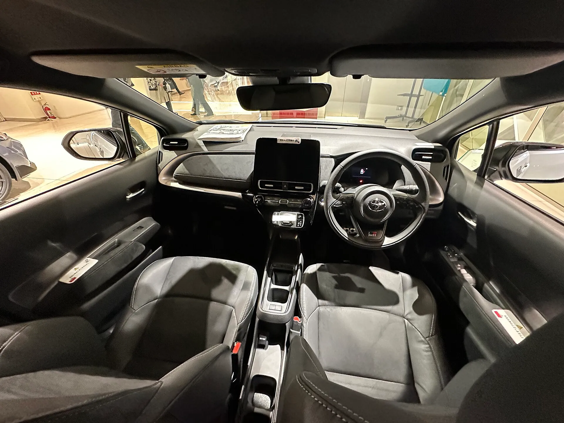 トヨタ アクア GR SPORTの運転席まわり。右ハンドルで、センターにディスプレイオーディオが縦に立ち、ステアリングにGRのロゴが入る