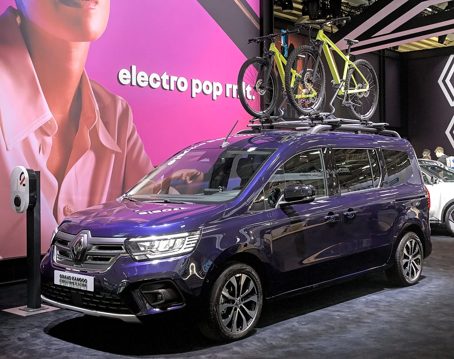 欧州仕様のグラン カングー E-Tech（EV）を左前方から見た外観。ボンネットの先に「GRAND KANGOO」のプレートが置かれ、屋根には自転車を載せたキャリアが付く