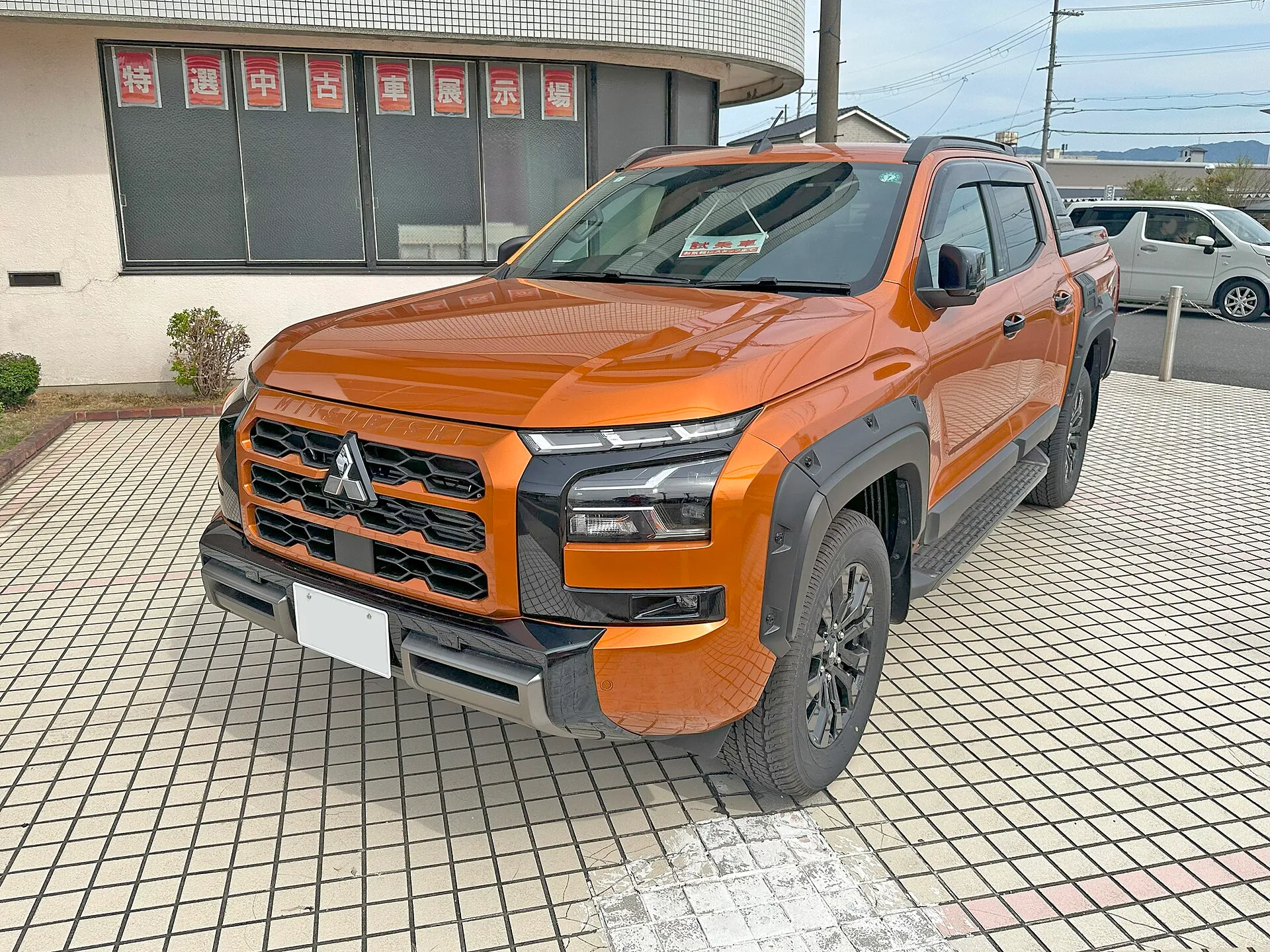 オレンジのトライトン GSR を左前方から見た外観。黒いホイールアーチモール、黒い18インチアルミホイール、ルーフレールを装着している