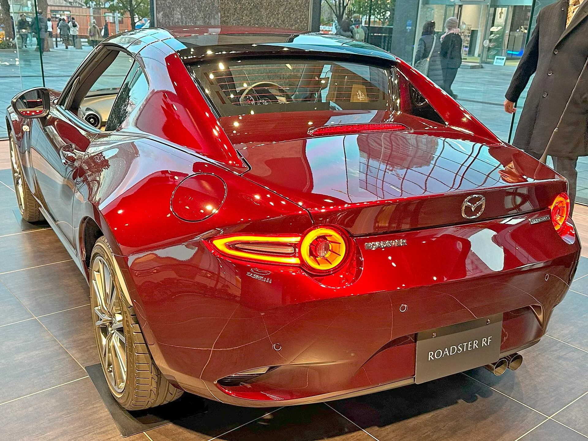 濃い赤のマツダ ロードスター RF 35th Anniversary（5BA-NDERE）を左後方から見た外観。金属のルーフからリアフェンダーへつながるファストバック形状と、丸いテールランプが見える