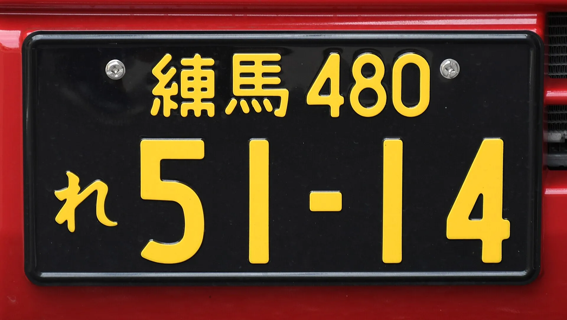 黒地に黄色い文字のナンバープレートを正面から写した写真。Wikimedia Commons の説明では、排気量660cm3未満の事業用車のものとされている