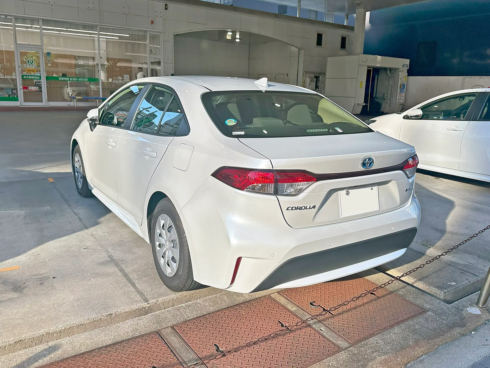 白いトヨタ カローラ X（ハイブリッド）を左後ろから見た外観。トランクリッドの後端が短く立ち上がり、15インチのスチールホイールに樹脂フルキャップが付いている