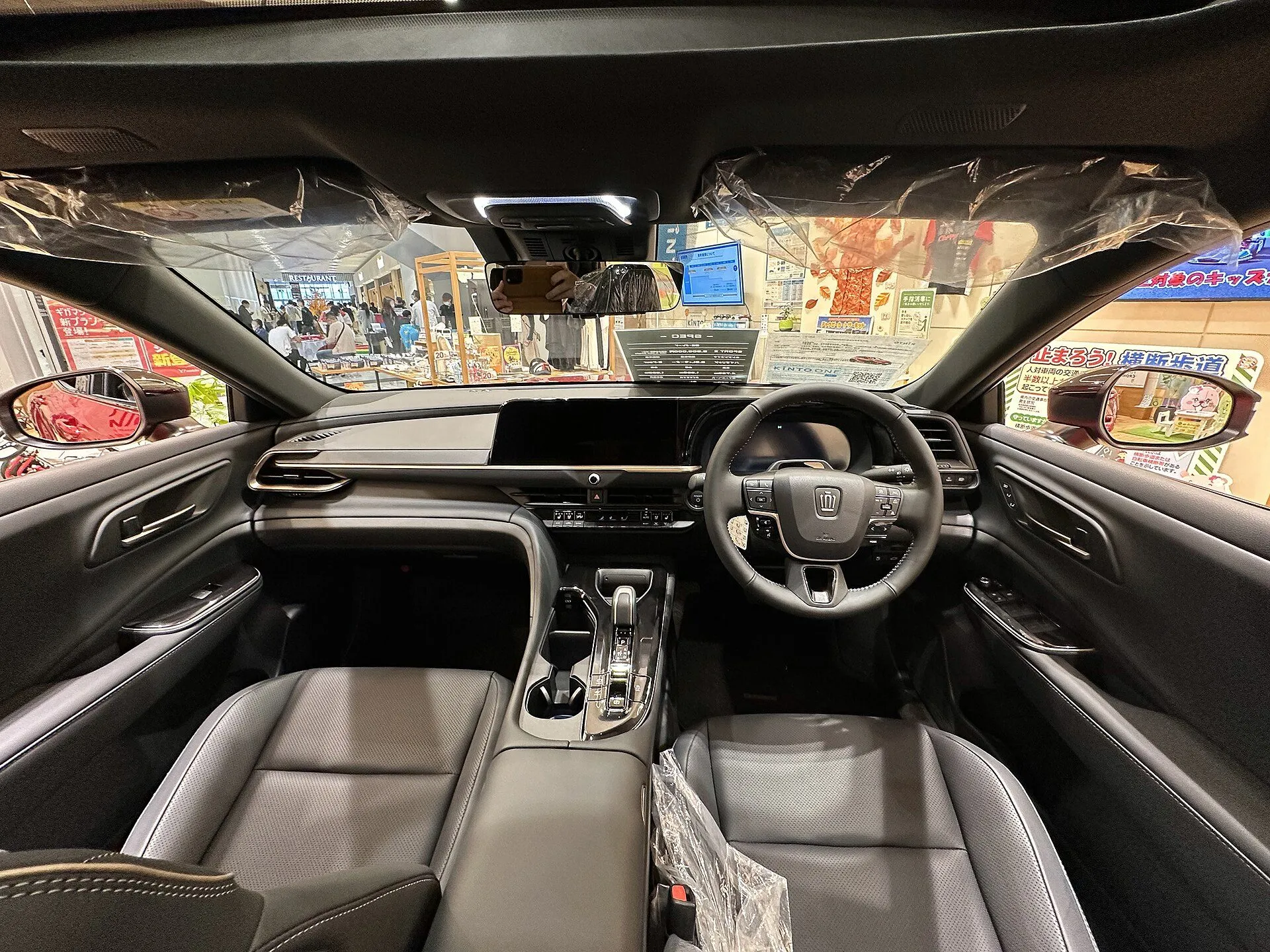 トヨタ クラウン（スポーツ）SPORT Z（ハイブリッド車・6AA-AZSH36W-BNXGB）の運転席まわりを後席側から見た様子。黒い前席2つの間にセンターコンソールがあり、ダッシュボードの中央に横長のディスプレイが付いている。2026年9月の一部改良より前の個体
