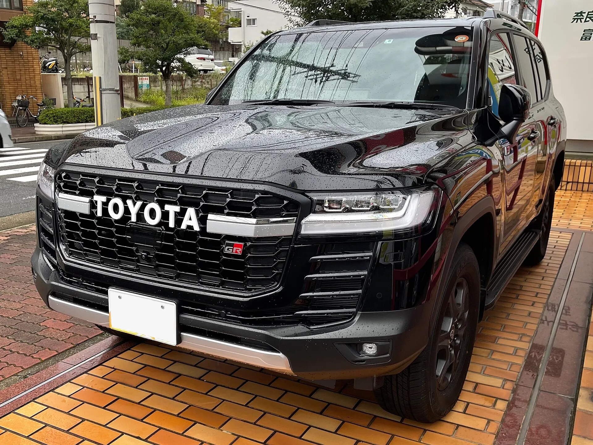 トヨタ ランドクルーザー“300” GR SPORT（3.3Lディーゼル車・3DA-FJA300W-GMUSY）を左斜め前から見た外観。黒いボディで、グリルに白い「TOYOTA」の文字とGRのエンブレムが付いている。2026年9月の一部改良より前の個体