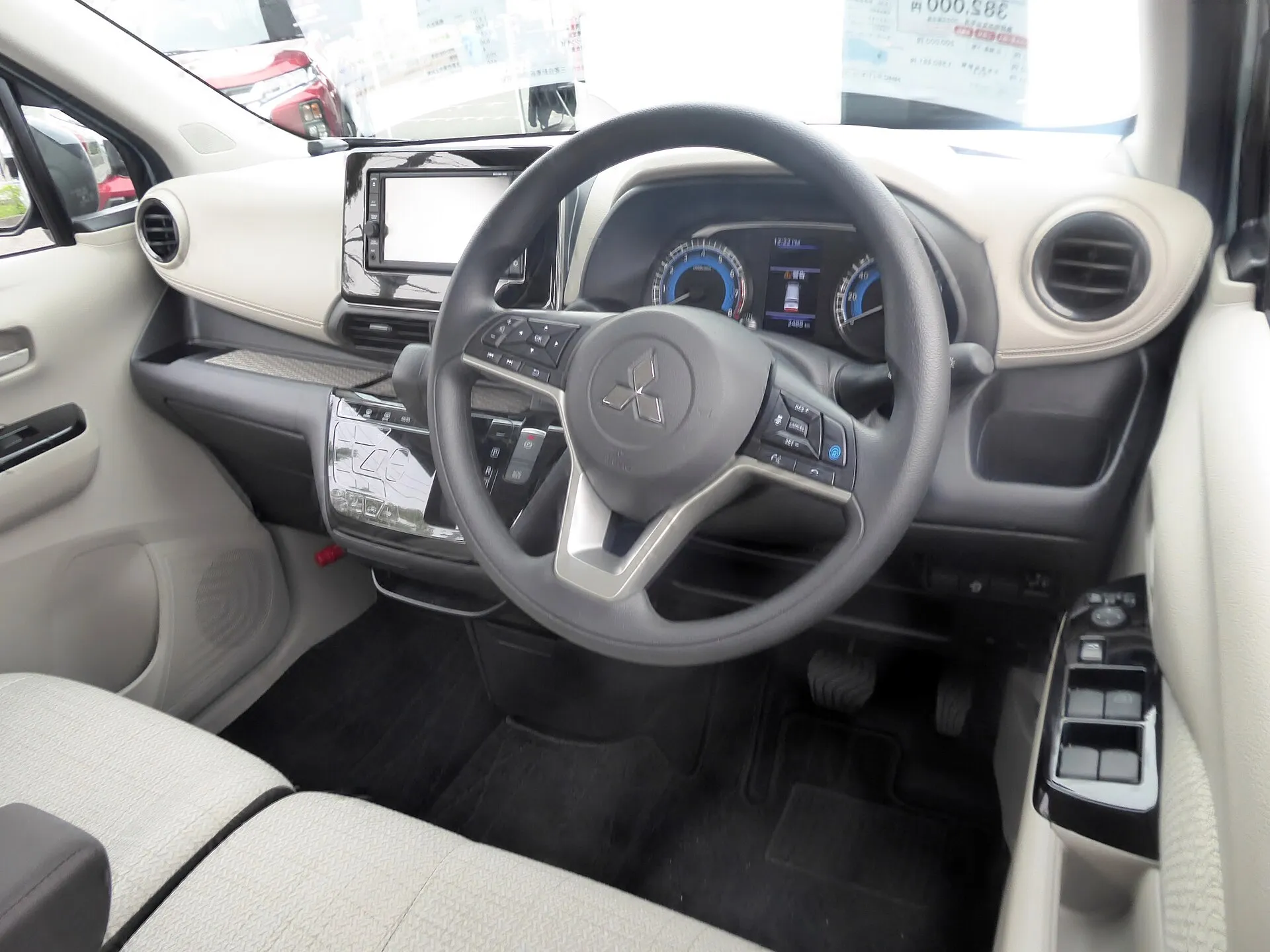 三菱 eKワゴン G（2WD）の運転席まわり。ステアリングの左、ナビの下に光沢のある平らなエアコンの操作パネルがある。2026年8月の一部改良より前の個体