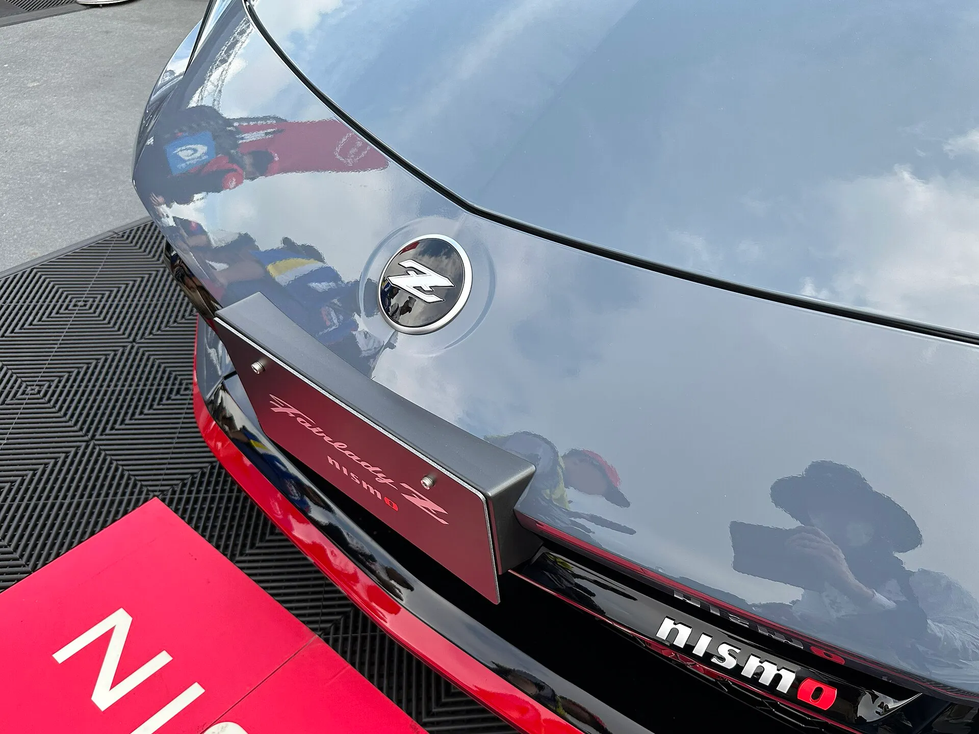 フェアレディZ NISMO の車体の先端。丸い枠の中にZの文字をかたどったエンブレムが付き、その下に Fairlady Z NISMO と書かれた板がある