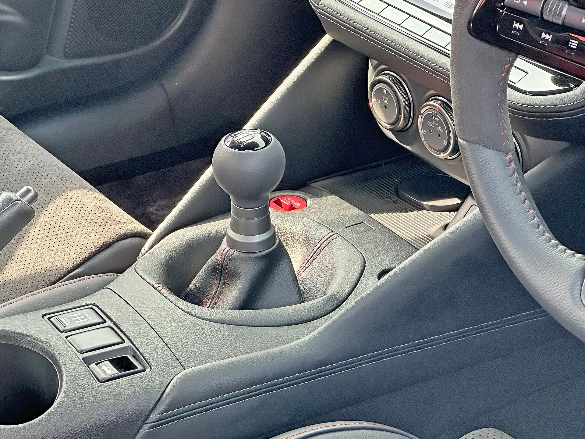 フェアレディZ NISMO 6速MT車のセンターコンソール。丸いシフトノブの頭に6速のシフトパターンが描かれ、その奥に D-MODE と書かれた赤いスイッチがある