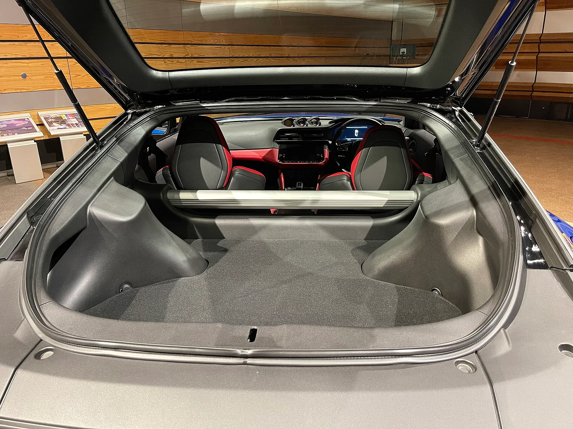 フェアレディZ Version ST(9M-ATx・5BA-RZ34型)のバックドアを開けたラゲッジ。座席のすぐ後ろまで床が続き、左右の張り出しのあいだにバーが1本渡っている。奥に赤と黒の座席が見える。2022年6月に撮影された、マイナーチェンジ前の個体