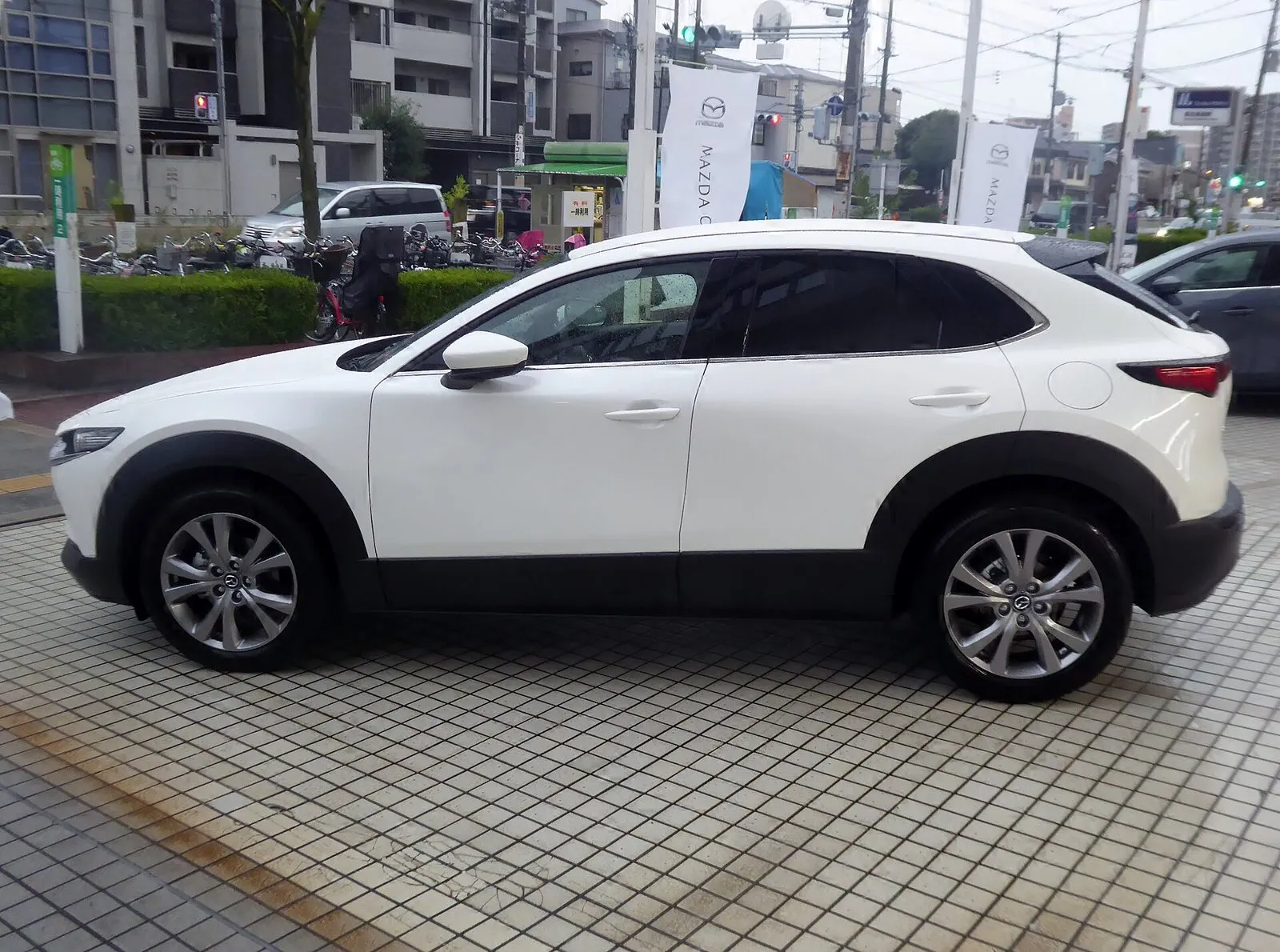 マツダ CX-30 20S PROACTIVE Touring Selection（2WD・5BA-DMEP）を左真横から見た外観。白い車体で、屋根は後ろへ向かって低くなり、タイヤのまわりと車体の下側は黒い樹脂で覆われている。2026年7月の商品改良より前の個体