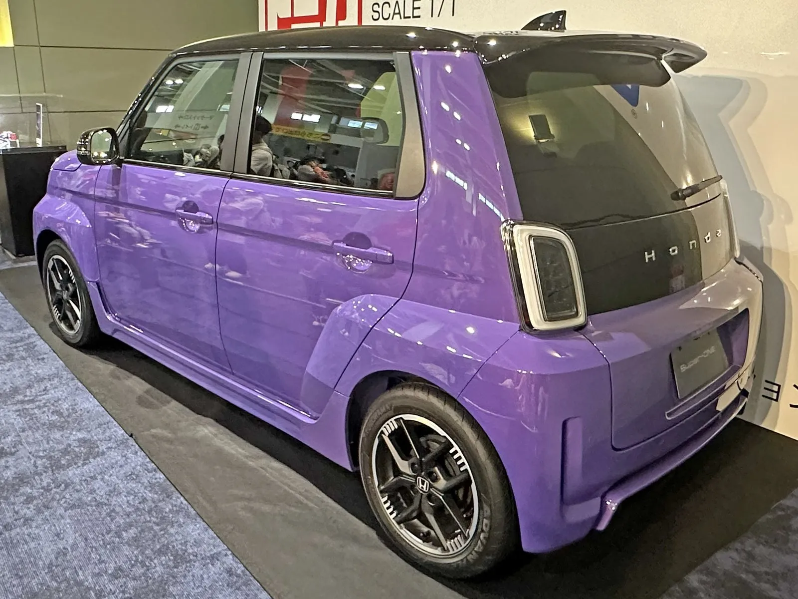ホンダ Super-ONE（ZAA-JG6）を斜め後ろから見た外観。紫の車体に黒い屋根の2トーンで、屋根の後端に大きなテールゲートスポイラー、屋根の上にシャークフィンアンテナがある。後ろのタイヤのまわりが外へ張り出し、黒いアルミホイールが付いている。屋内に置かれた展示車